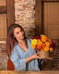 Lorena enseña la bombonera de cempasúchil y terciopelo para el Día de Muertos, terminada en el taller