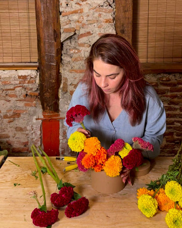 Lorena montando una bombonera con cempasúchil naranja y amarillo y terciopelo rojo en el taller de C/ Ruda 15, Madrid