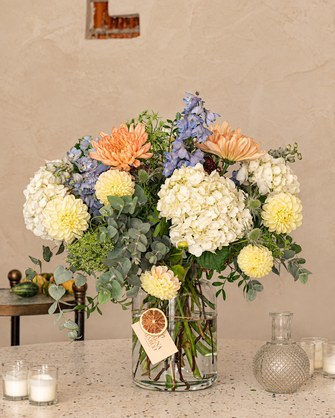 Ramo de hortensias pastel con flores en tonos crema, melocotón y azul suave, en jarrón de cristal